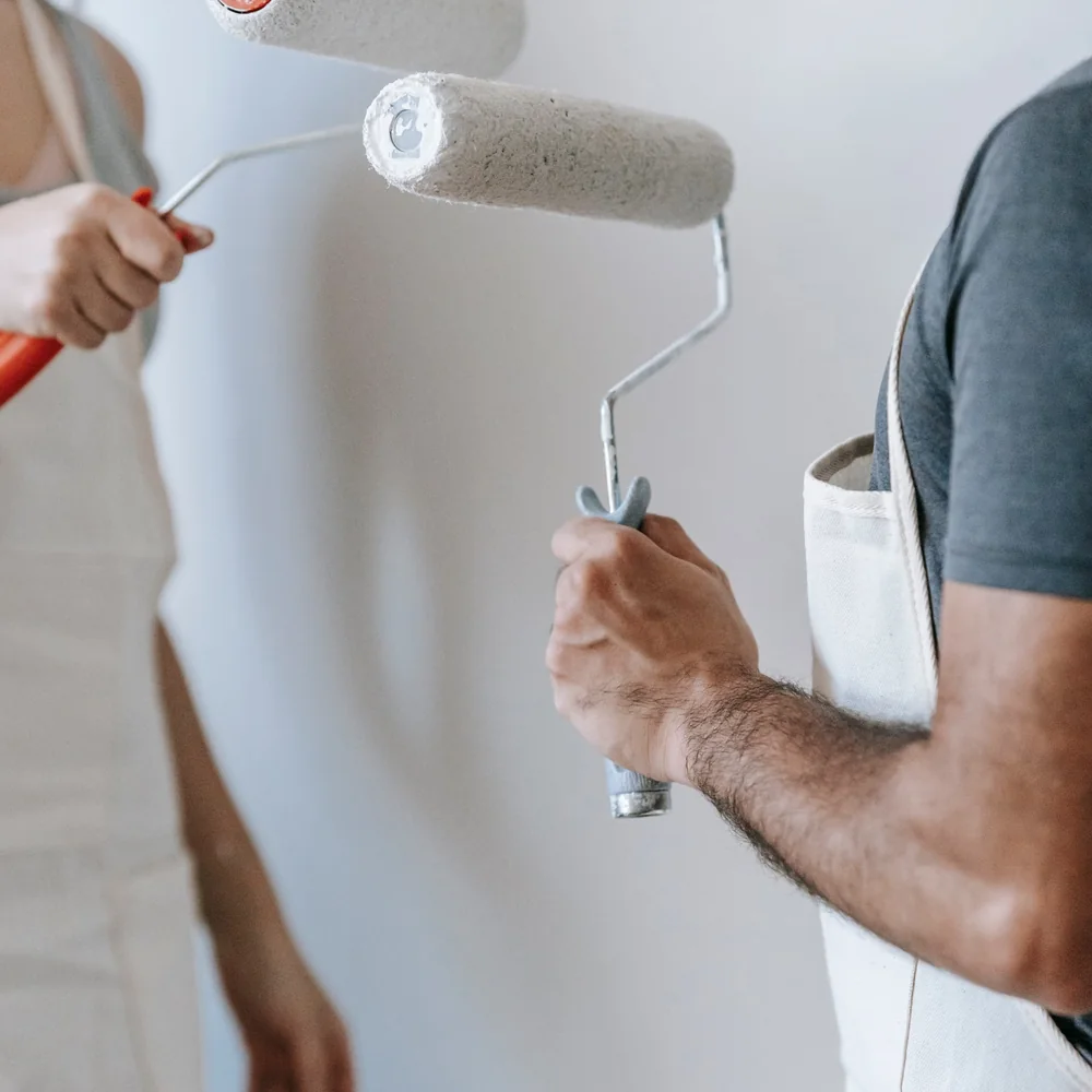 Application d'une couche de peinture blanche au rouleau sur un mur.